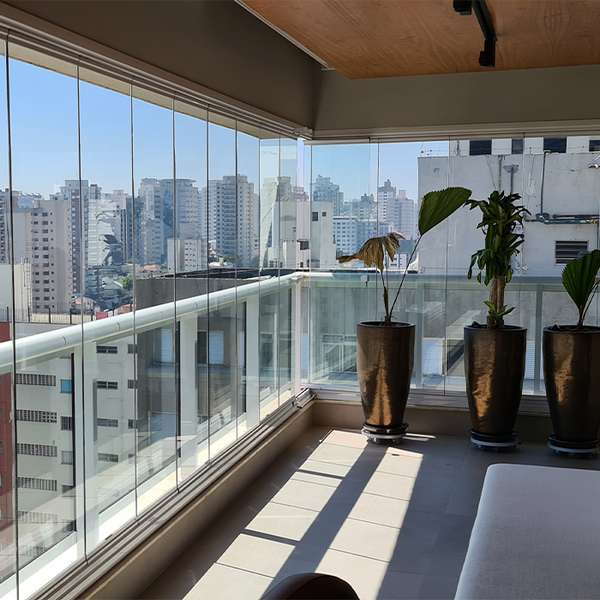 Sacada ampla fechada com painéis de vidro e vista urbana